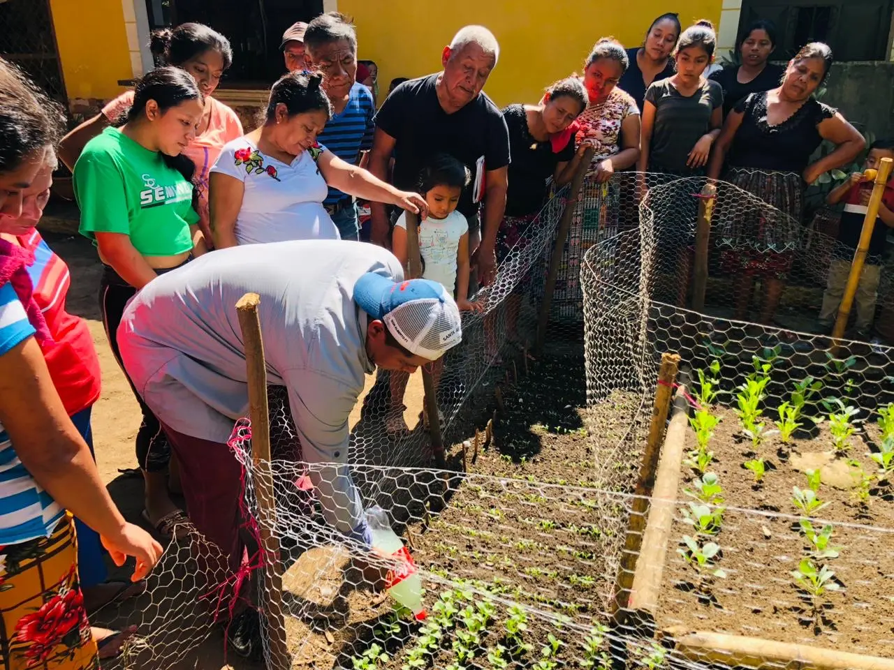 A facilitator in a traditional woven top teaching participants as they take notes on clipboards